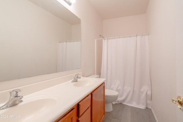 bathroom featuring a sink, toilet, double vanity, and wood finished floors