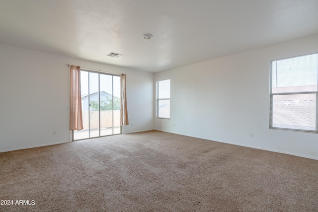 empty room featuring visible vents, baseboards, and light colored carpet