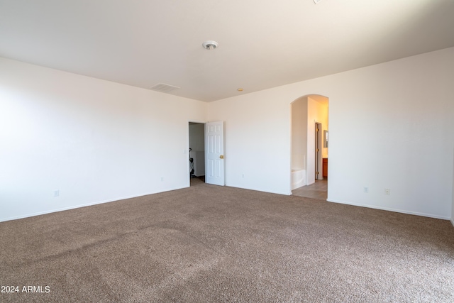 unfurnished room with carpet floors, arched walkways, and baseboards