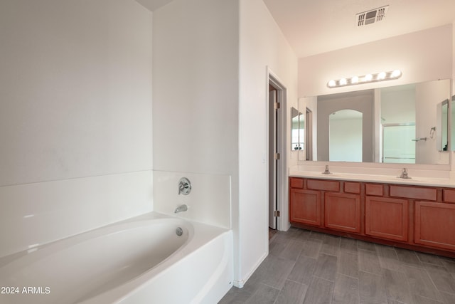 full bathroom with double vanity, visible vents, a sink, and a garden tub