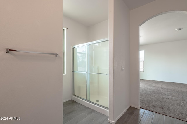 full bath featuring baseboards, a shower stall, and wood finished floors