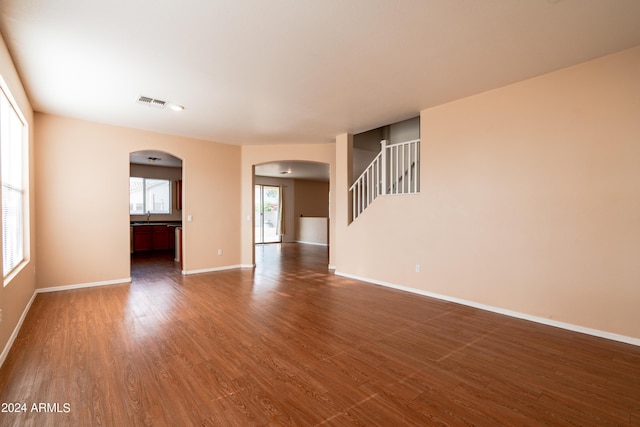 interior space featuring arched walkways, baseboards, dark wood-style floors, and stairs