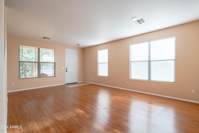 empty room featuring baseboards, light wood finished floors, and visible vents