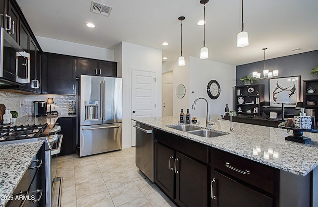 kitchen featuring tasteful backsplash, visible vents, appliances with stainless steel finishes, a sink, and light stone countertops