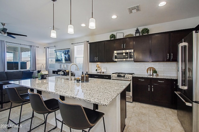 kitchen with stainless steel appliances, a sink, visible vents, open floor plan, and backsplash