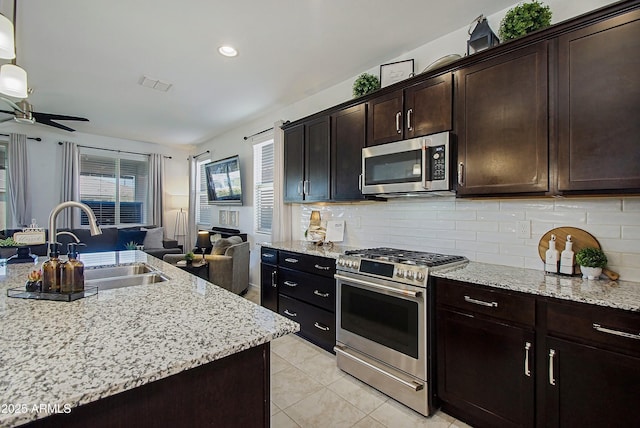 kitchen with visible vents, appliances with stainless steel finishes, open floor plan, a sink, and backsplash