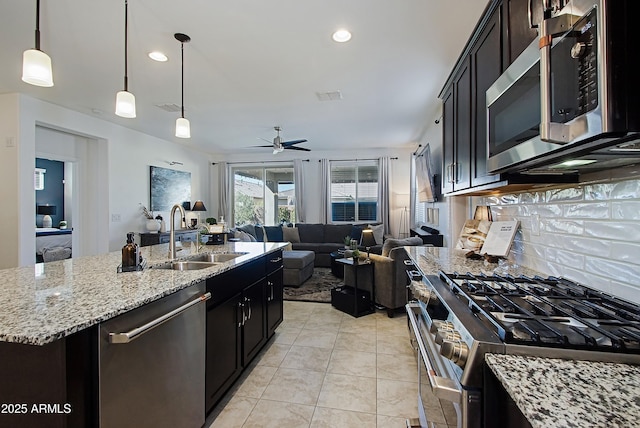 kitchen with stainless steel appliances, visible vents, backsplash, open floor plan, and a sink