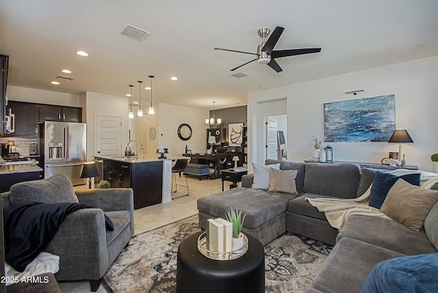 living area featuring light tile patterned floors, recessed lighting, visible vents, and ceiling fan with notable chandelier