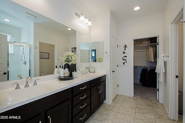 bathroom featuring double vanity, a stall shower, a sink, and recessed lighting