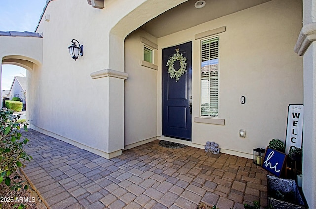 entrance to property featuring a patio and stucco siding