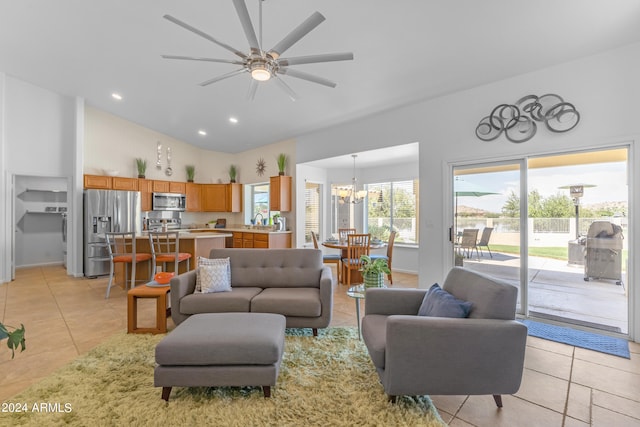 tiled living room with high vaulted ceiling and ceiling fan with notable chandelier