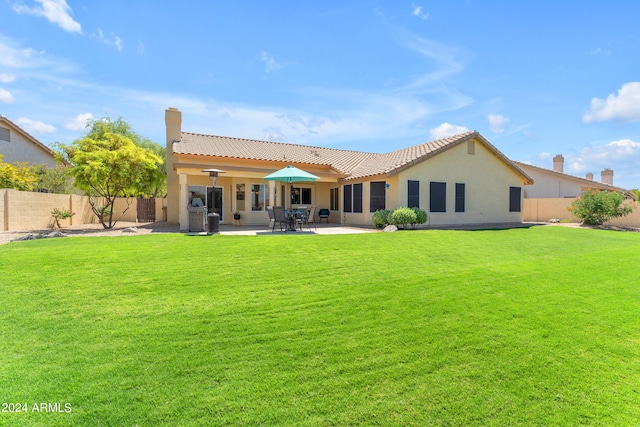 back of property with a lawn and a patio