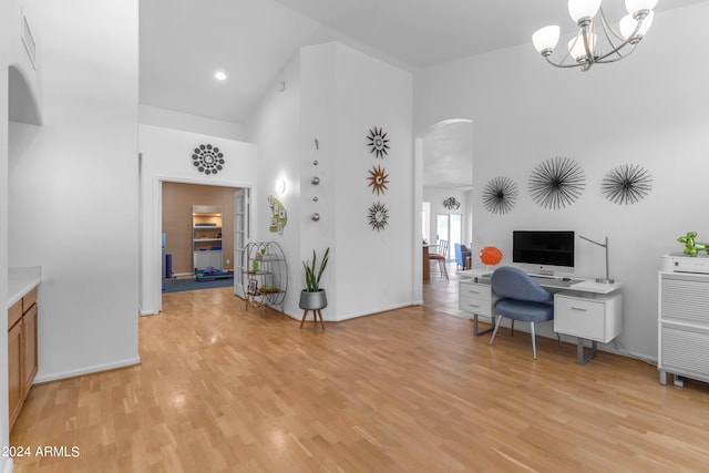 interior space with light hardwood / wood-style flooring, a high ceiling, and a notable chandelier