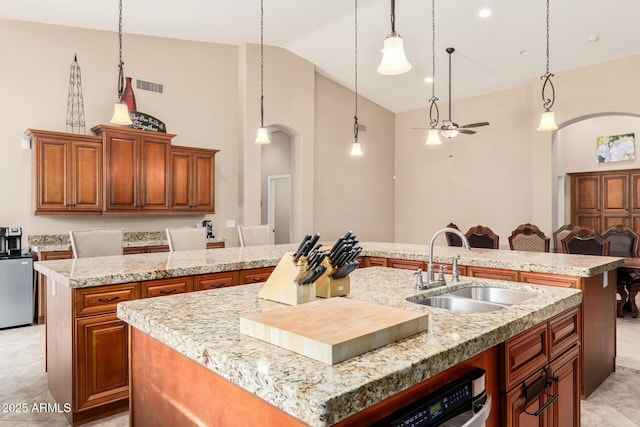 kitchen featuring arched walkways, visible vents, a sink, and a kitchen island with sink