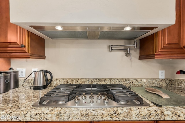 kitchen with stainless steel gas stovetop and exhaust hood