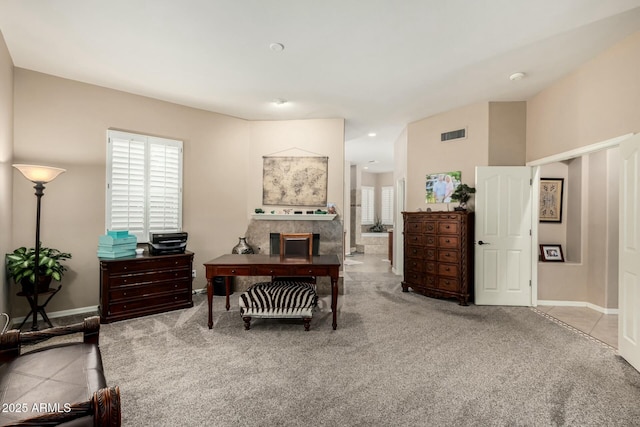 carpeted office with a wealth of natural light, baseboards, visible vents, and a tiled fireplace