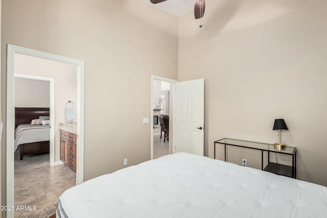 bedroom with baseboards, ensuite bath, a towering ceiling, and a ceiling fan