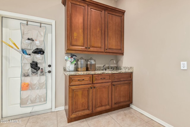 bar featuring a sink, baseboards, and light tile patterned floors