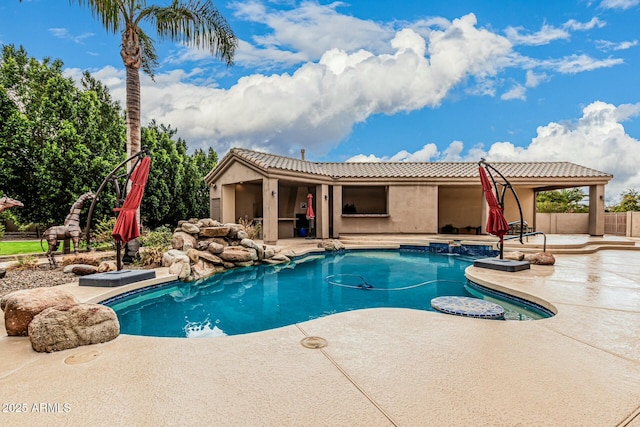 pool with a patio, fence, and a jacuzzi