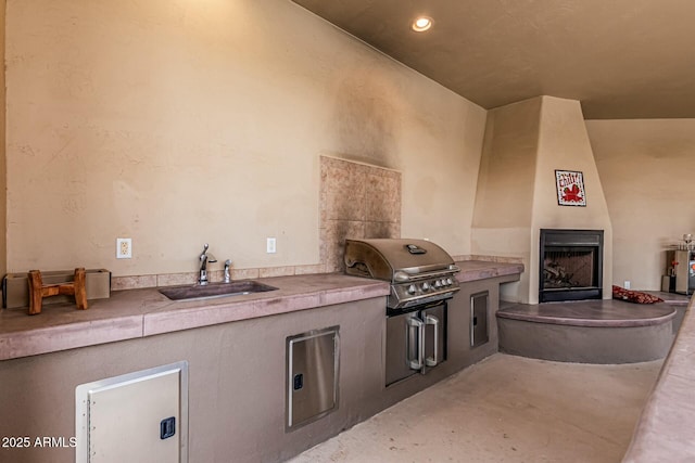 view of patio / terrace with a fireplace, a sink, and area for grilling