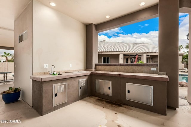 view of patio / terrace featuring area for grilling, a sink, and visible vents