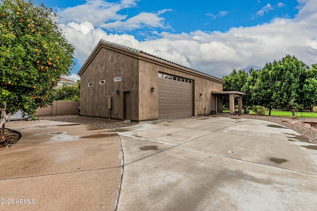 garage featuring driveway and fence