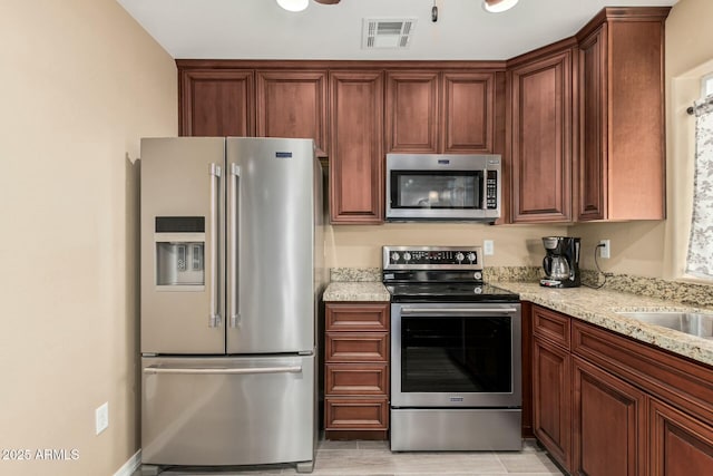 kitchen with appliances with stainless steel finishes, visible vents, a sink, and light stone counters