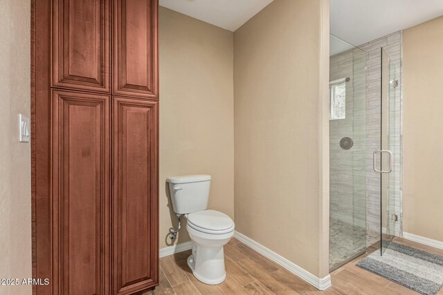 full bath featuring a stall shower, baseboards, toilet, and wood tiled floor