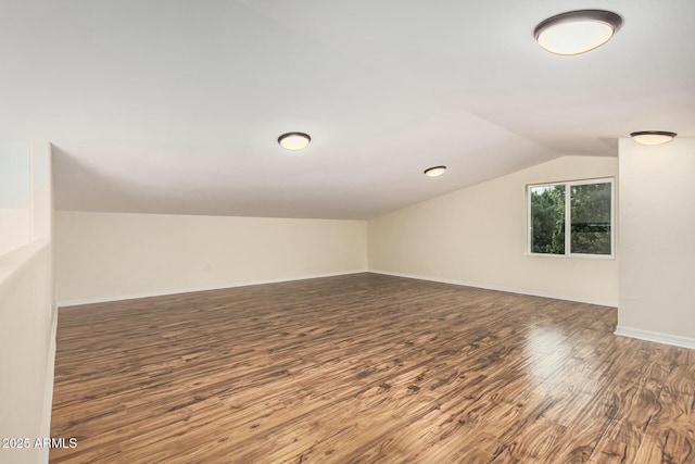 additional living space with vaulted ceiling, wood finished floors, and baseboards