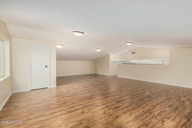 bonus room with vaulted ceiling, wood finished floors, visible vents, and baseboards