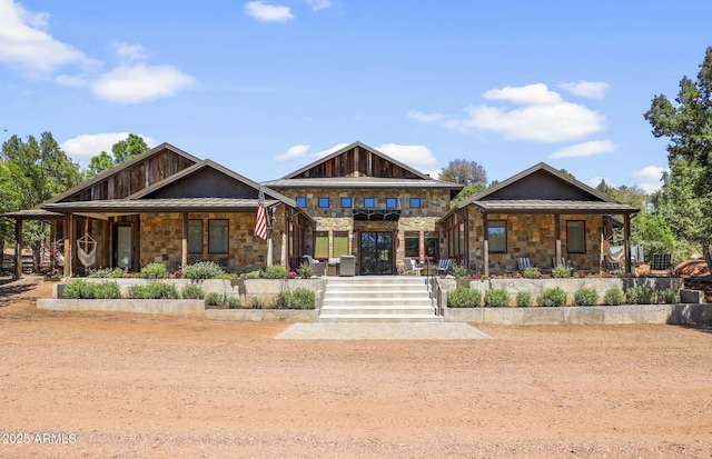 view of front of property featuring stone siding, metal roof, a porch, and a standing seam roof