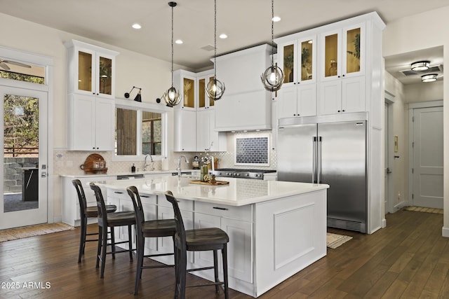 kitchen with a kitchen island with sink, stainless steel built in fridge, plenty of natural light, and a sink