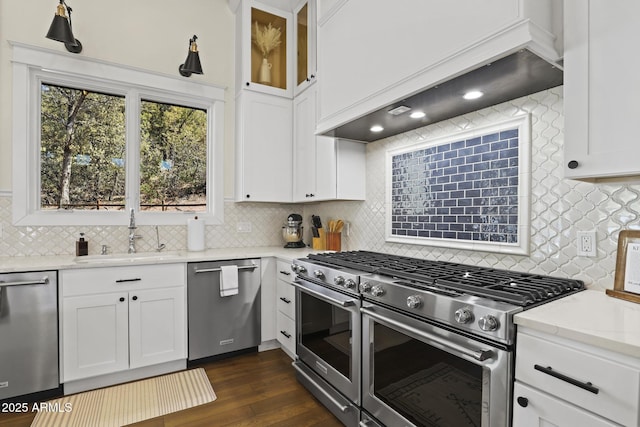 kitchen featuring premium range hood, white cabinetry, stainless steel appliances, and a sink