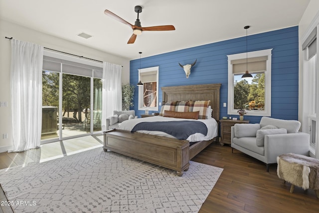 bedroom with access to exterior, multiple windows, visible vents, and hardwood / wood-style flooring