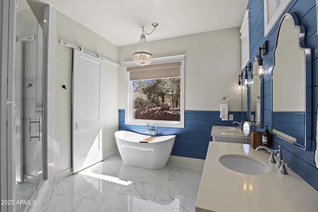 full bath with marble finish floor, a wainscoted wall, a sink, and a shower stall