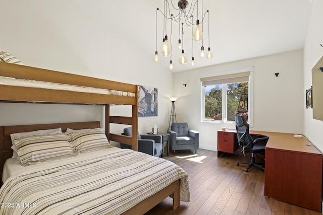 bedroom with wood-type flooring, a chandelier, and vaulted ceiling