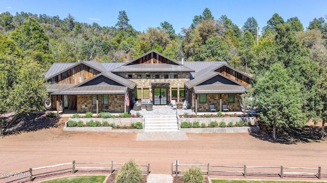 exterior space featuring covered porch, stone siding, and a standing seam roof