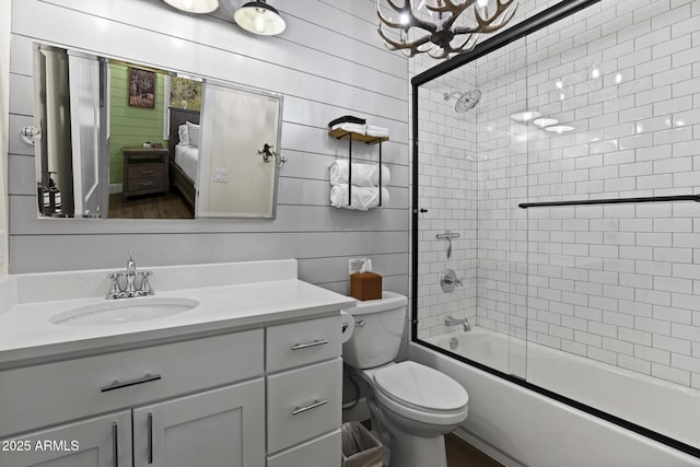 bathroom featuring toilet, shower / bath combination with glass door, and vanity