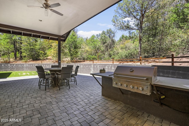 view of patio featuring fence, outdoor dining area, a ceiling fan, and area for grilling