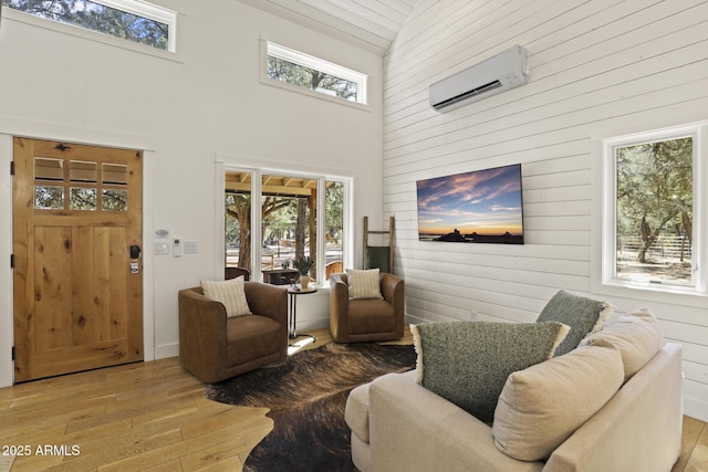 living area featuring wooden walls, a high ceiling, wood finished floors, and a wall mounted AC