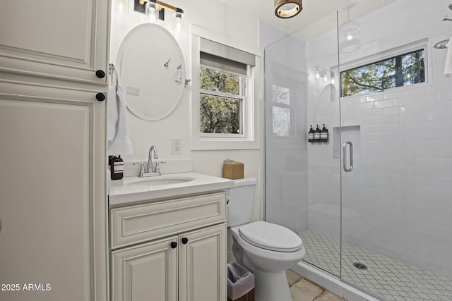 bathroom with a stall shower, vanity, and toilet