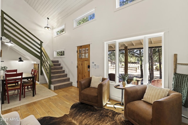 living area featuring high vaulted ceiling, hardwood / wood-style floors, stairway, and a healthy amount of sunlight