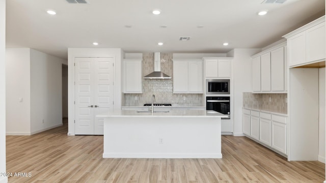 7384 W Buckhorn Trl, Peoria, AZ 85383 - kitchen with wall chimney exhaust hood, oven, stainless steel microwave, a kitchen island with sink, and light countertops