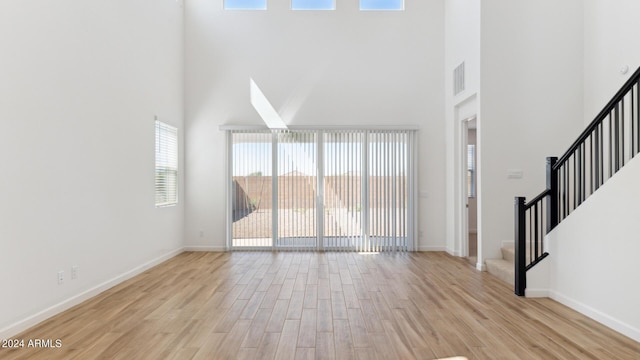 7384 W Buckhorn Trl, Peoria, AZ 85383 - unfurnished living room featuring a high ceiling, light wood-style floors, stairs, and baseboards