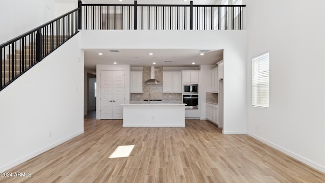 7384 W Buckhorn Trl, Peoria, AZ 85383 - kitchen with wall chimney range hood, stainless steel appliances, white cabinets, open floor plan, and a high ceiling