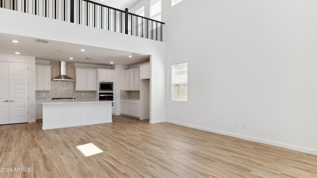 7384 W Buckhorn Trl, Peoria, AZ 85383 - kitchen with wall chimney exhaust hood, stainless steel microwave, oven, tasteful backsplash, and white cabinetry