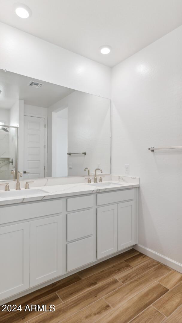 7384 W Buckhorn Trl, Peoria, AZ 85383 - bathroom featuring double vanity, a stall shower, and wood finished floors