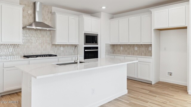 7384 W Buckhorn Trl, Peoria, AZ 85383 - kitchen featuring wall chimney exhaust hood, black oven, a sink, built in microwave, and an island with sink