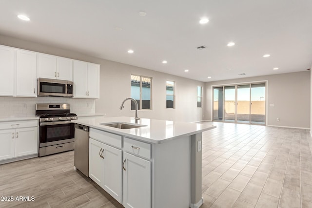 kitchen with sink, white cabinets, a kitchen island with sink, and appliances with stainless steel finishes