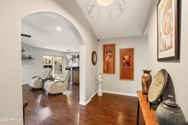 corridor with a notable chandelier, baseboards, arched walkways, and wood finished floors